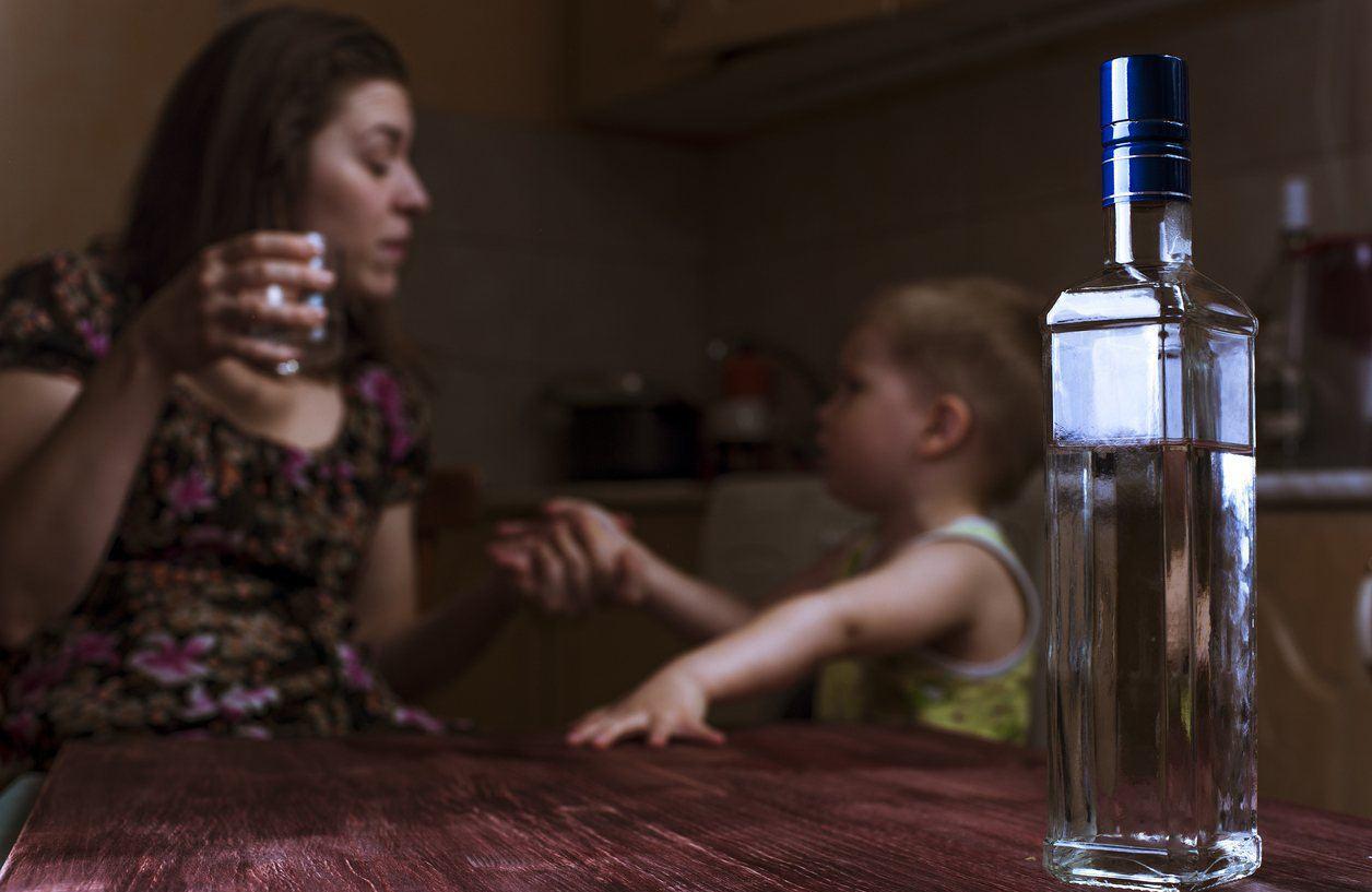 На фото ‒ мать употребляет алкоголь при маленьком ребенке